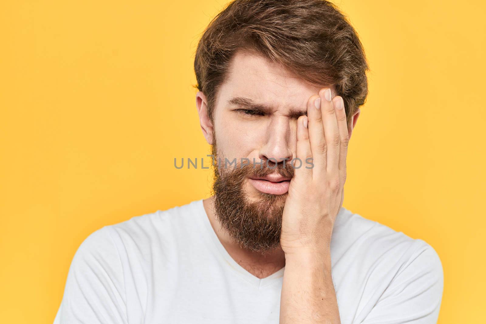 Man in white t-shirt emotions studio gestures with hands displeased facial expression yellow background. High quality photo
