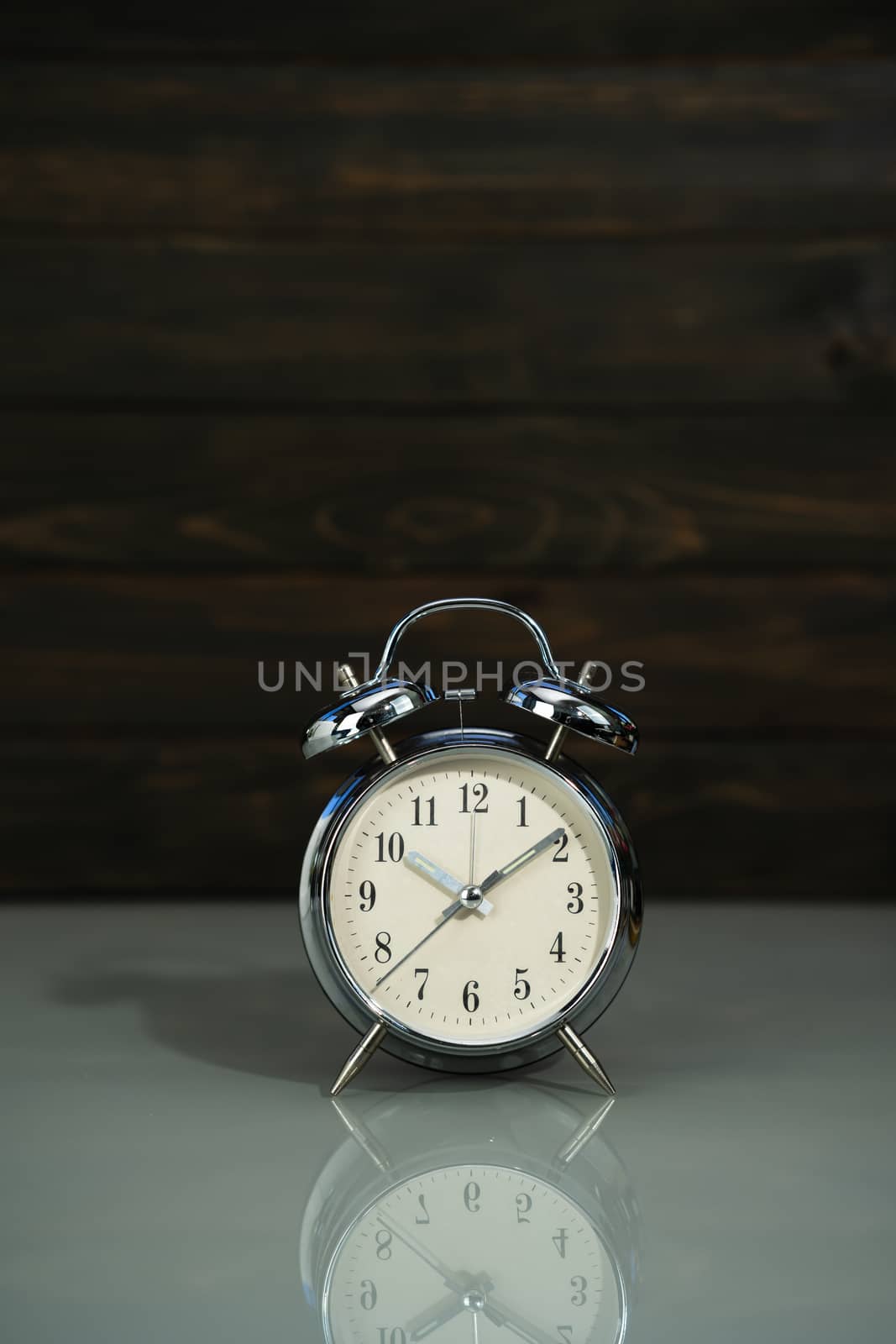 Retro alarm clock on table near wood background