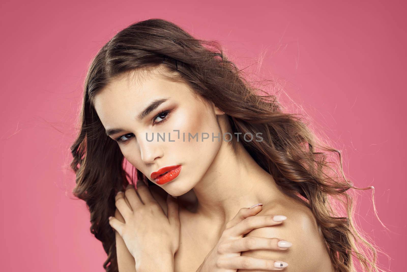 Beautiful woman with red lips on a pink background nude shoulders cropped view. High quality photo