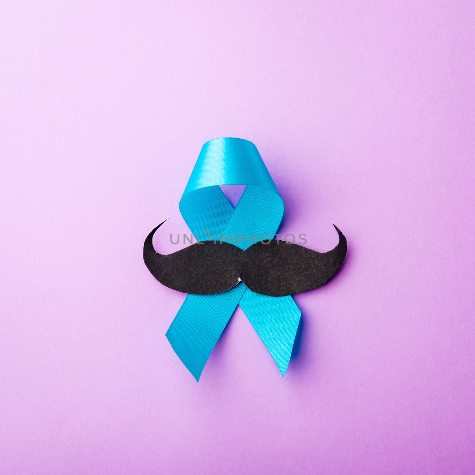 Black mustache paper and light blue ribbon, studio shot isolated on purple background, Prostate cancer awareness month, Fathers day, minimal November moustache concept