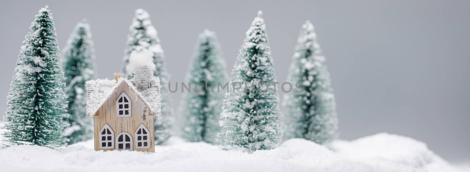 Christmas and New Year card, toy house in the snow in fir forest. Winter holidays and celebration concept.