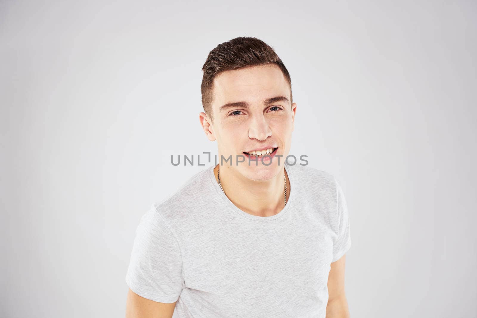 Man in a white t-shirt emotions gestures with hands close-up cropped view light background by SHOTPRIME