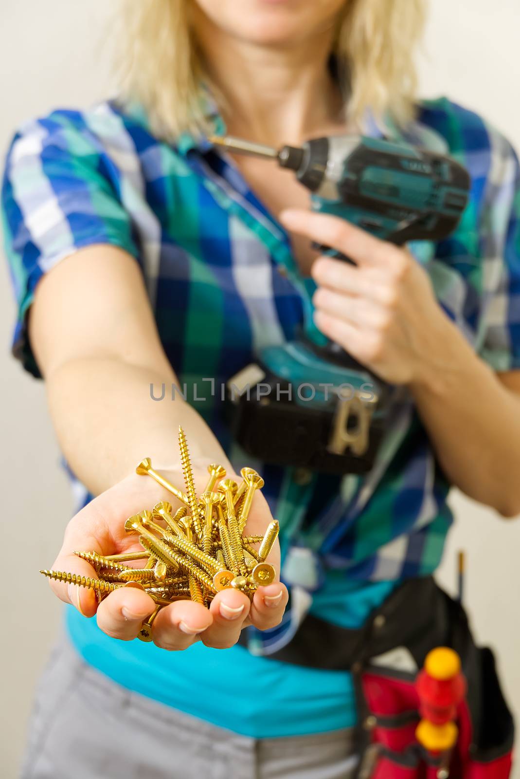 Female hands holding a handful of screws Hands show the golden screws . Home work, handywoman concept. by PhotoTime