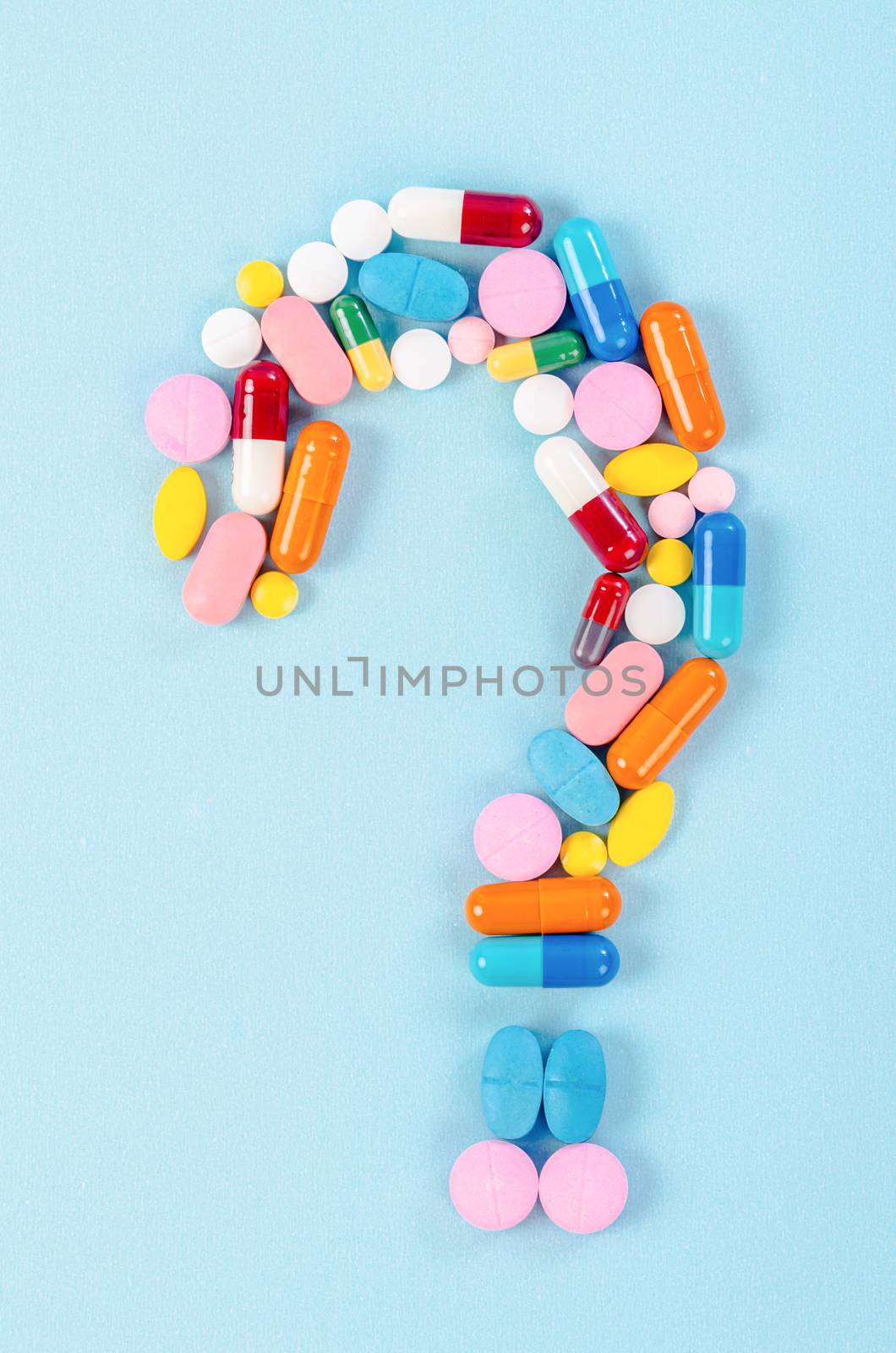 A question mark from laid out of medicine pills on blue background.