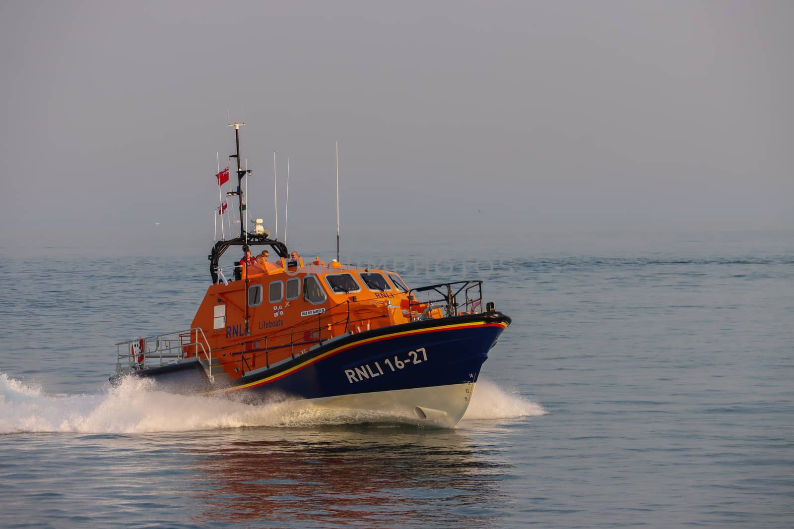 A team of coast guards on a RNLI Lifeboat travelling over the ocean, leaving from the Mumbles, Swansea, Wales, UK on a misty day on a rescue mission