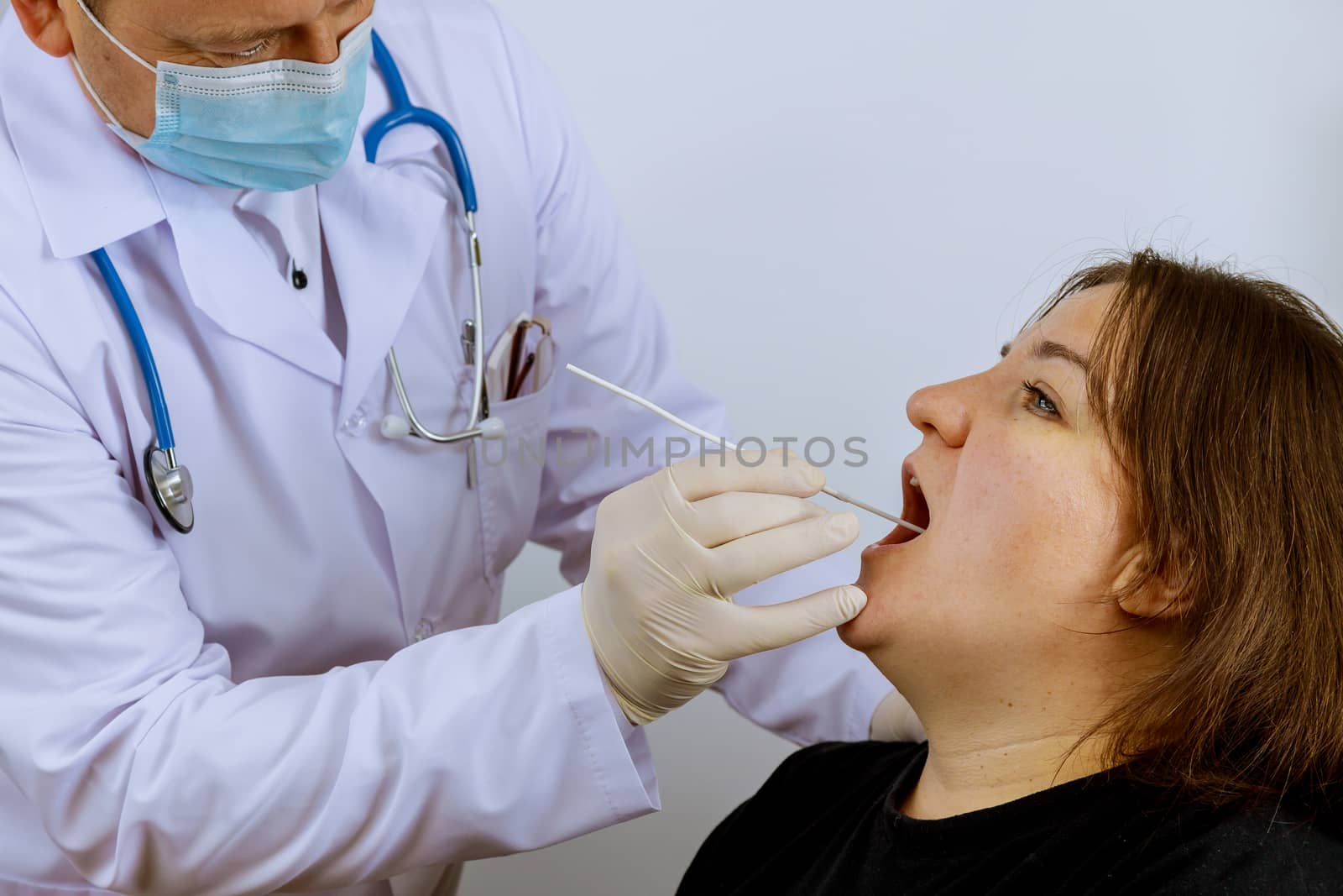 Healthcare worker with equipment performs coronavirus swab on woman on mouth swab for coronavirus COVID-19.