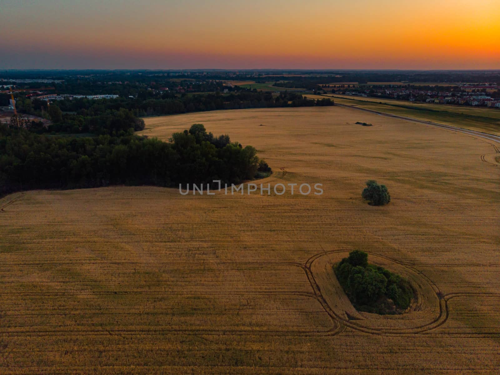 Aerial view to rising sun over fields village and forest at morning by Wierzchu