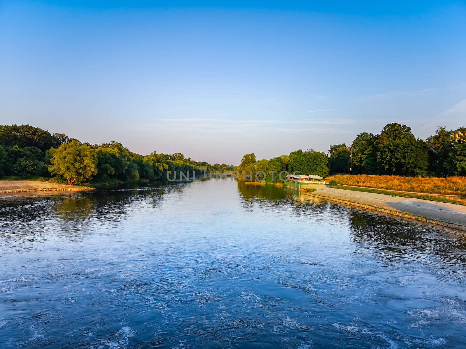 Long river with waves between trees at sunny morning