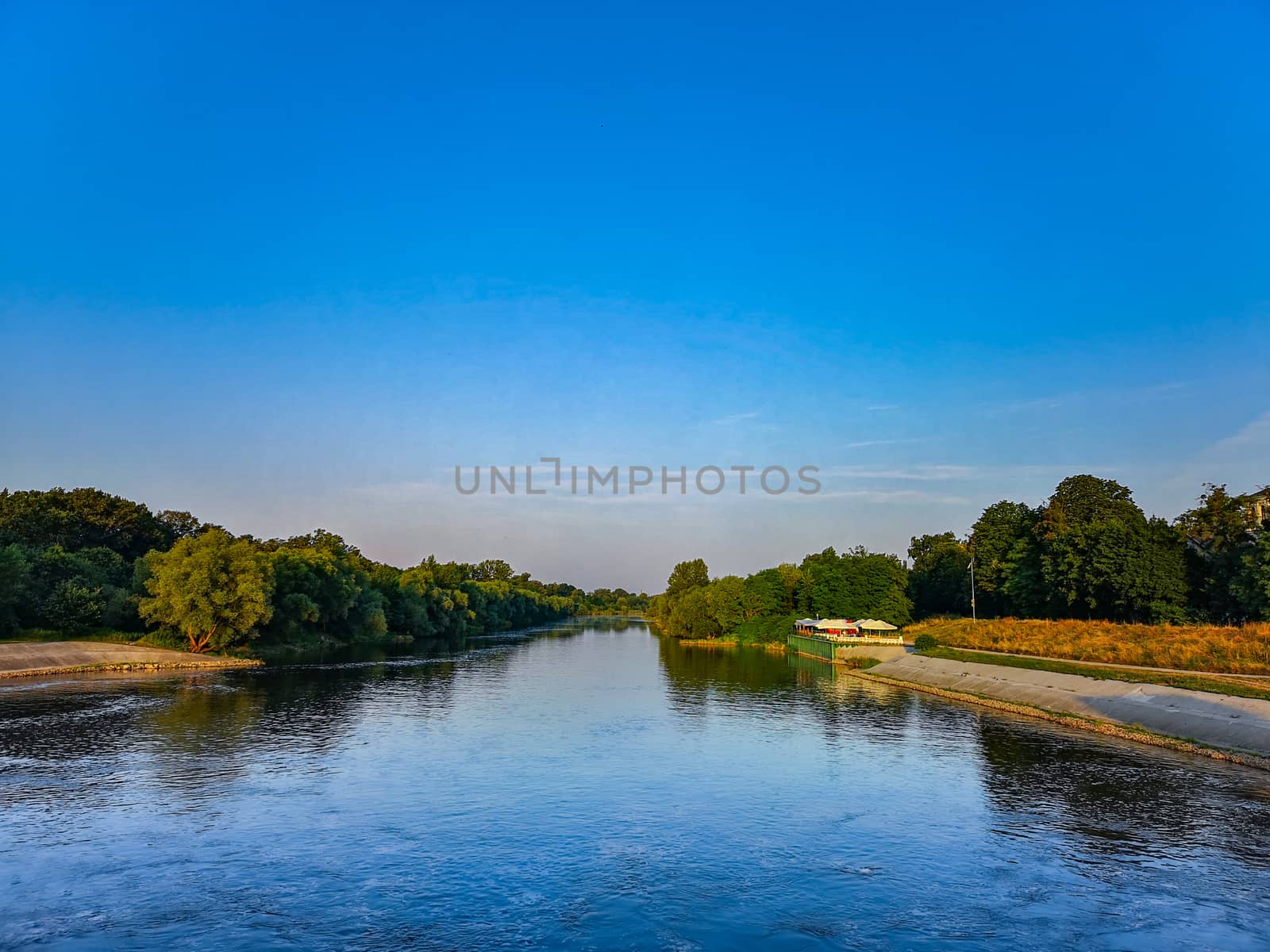 Long river with waves between trees at sunny morning