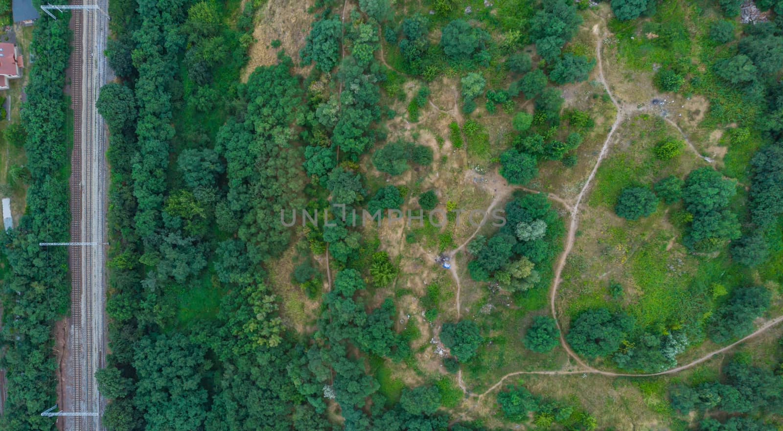 Top down aerial look to paths in park on hill and train rails on side