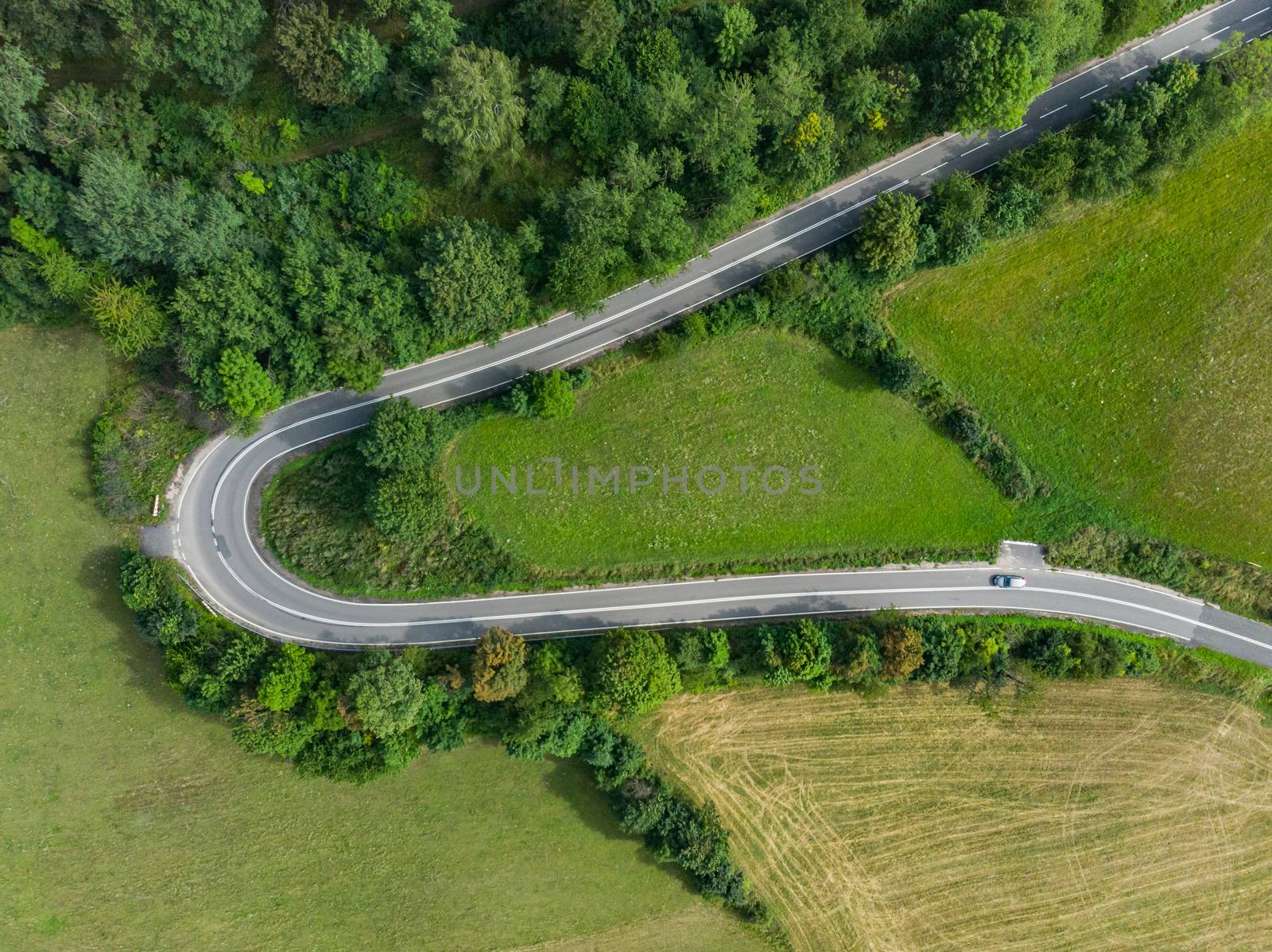 Aerial top down view to Hard curve on road near bushes and trees in mountains by Wierzchu