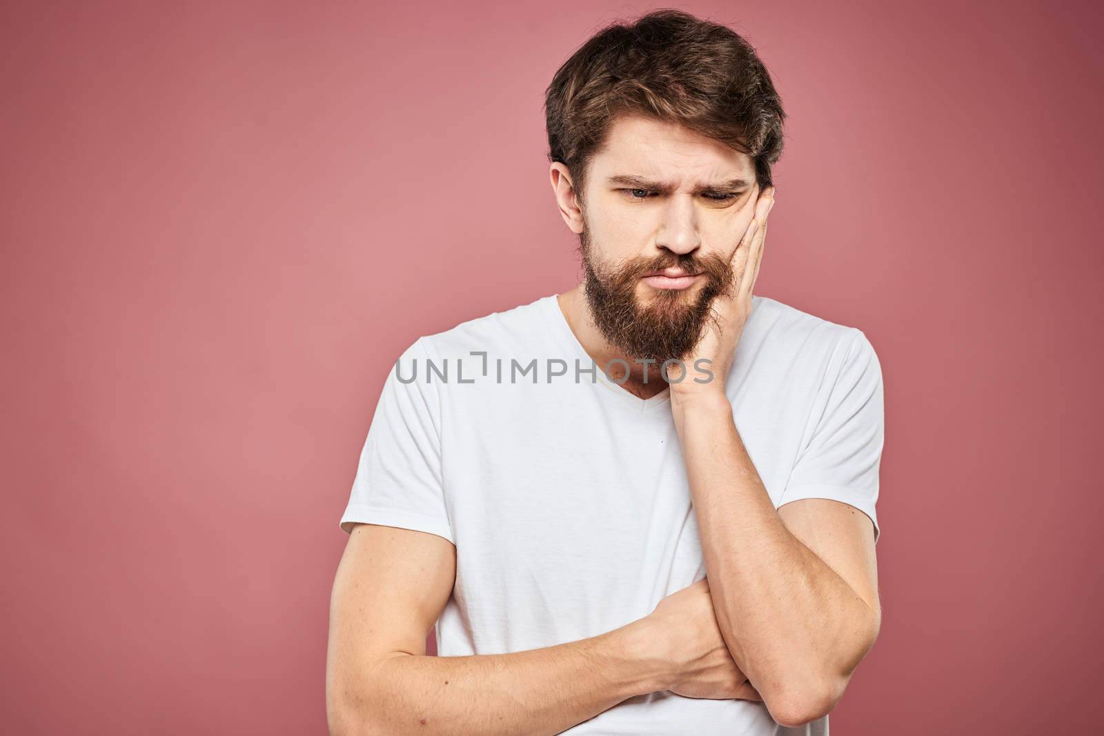 emotional man white t shirt sad facial expression pink background. High quality photo