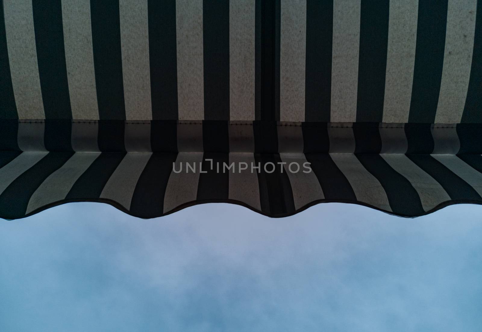 Upward view to shop awning with black and white stripes by Wierzchu