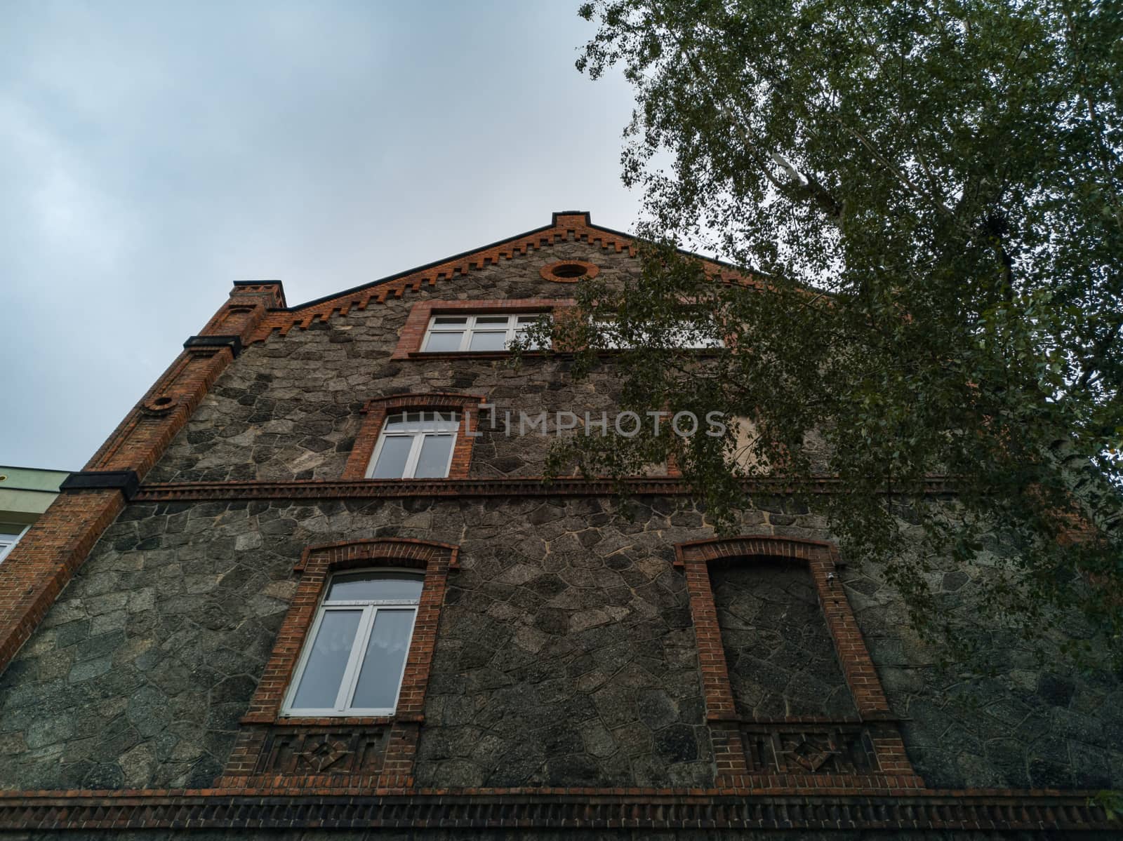 Upward view to old house made by stone and brick with window frame without window by Wierzchu