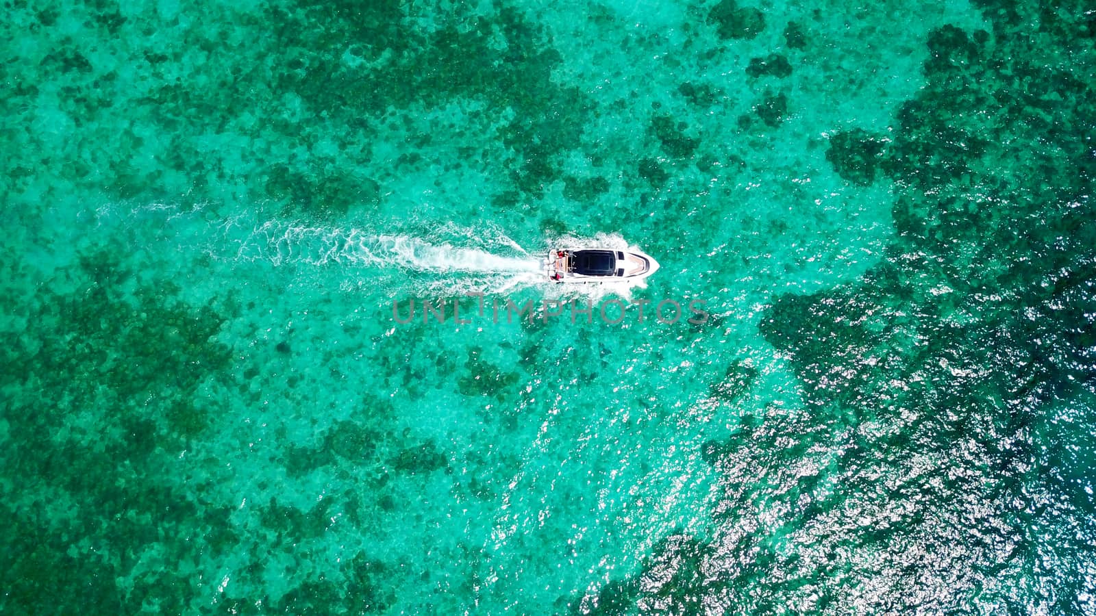 Turquoise clear water. Yachts, boats floating. Water Gradient from light to dark blue. Phi Phi don island, shooting from a drone from the air. White sand, green trees, palm trees and large hills.