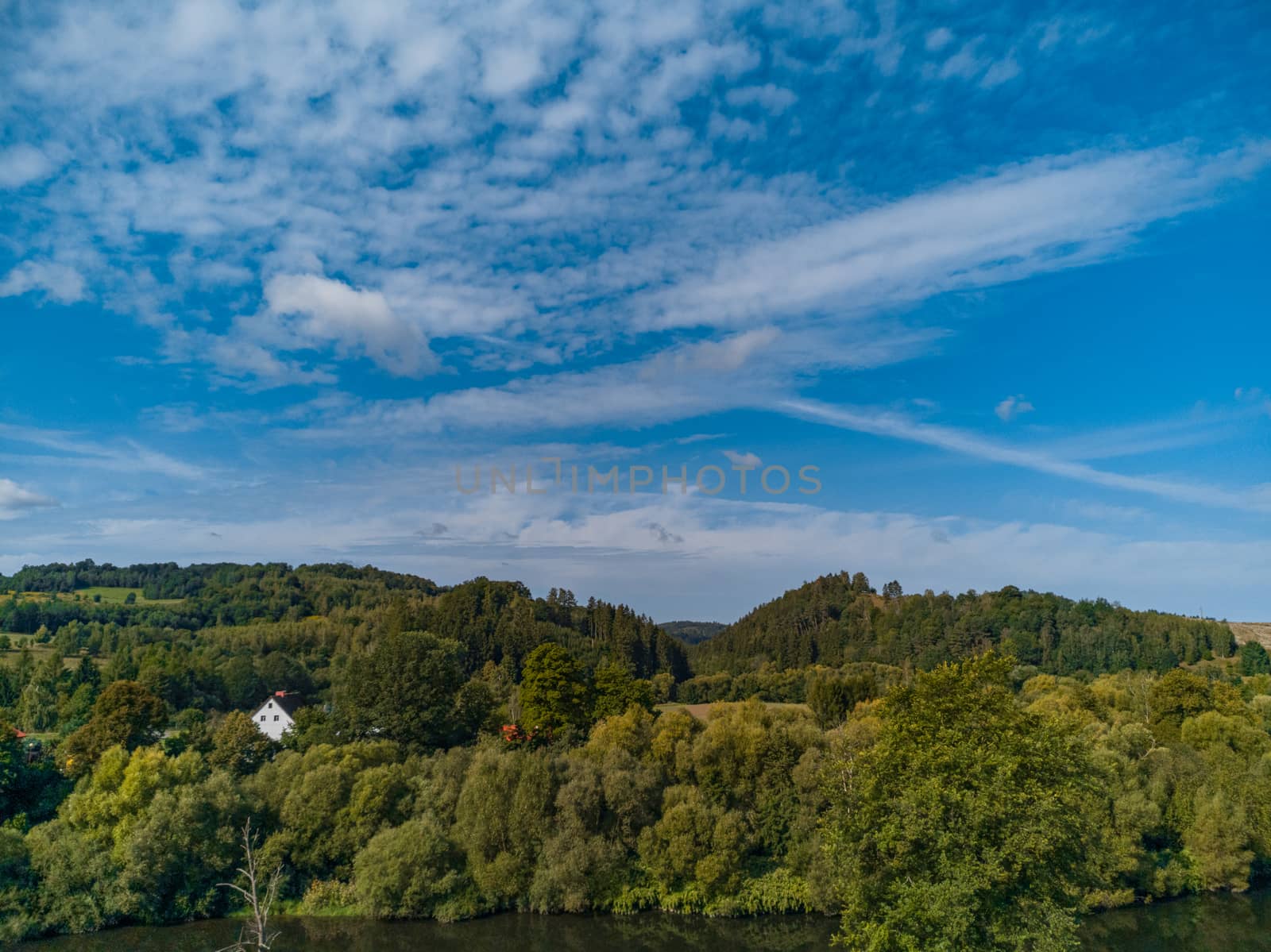 Hills and mountains full of trees and home between at sunny cloudy day by Wierzchu