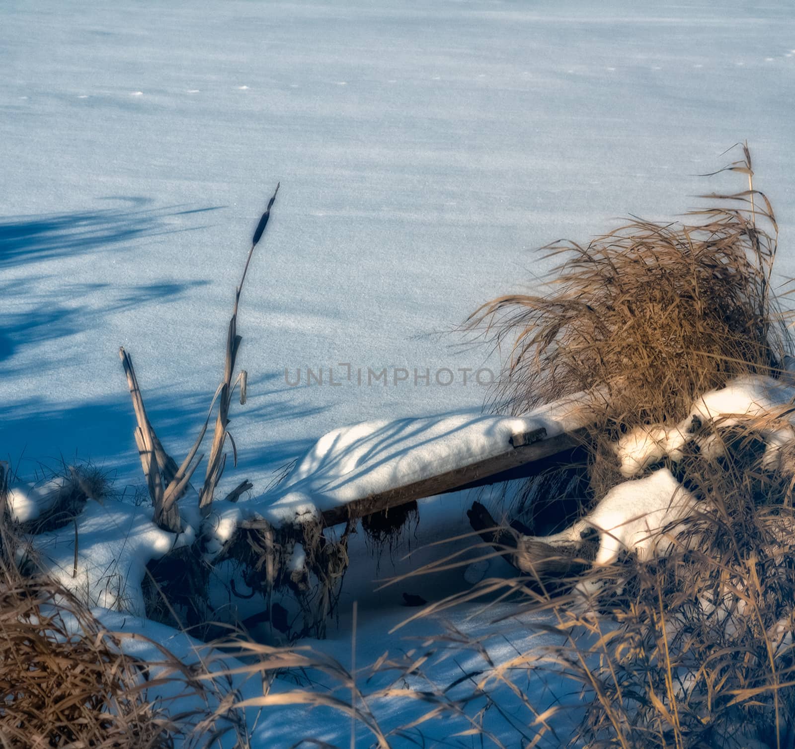 Broken wooden pier by the river in winter in the snow.