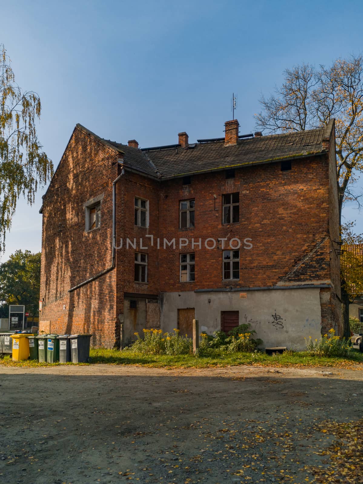 Old red brick block of flats between trees and bushes