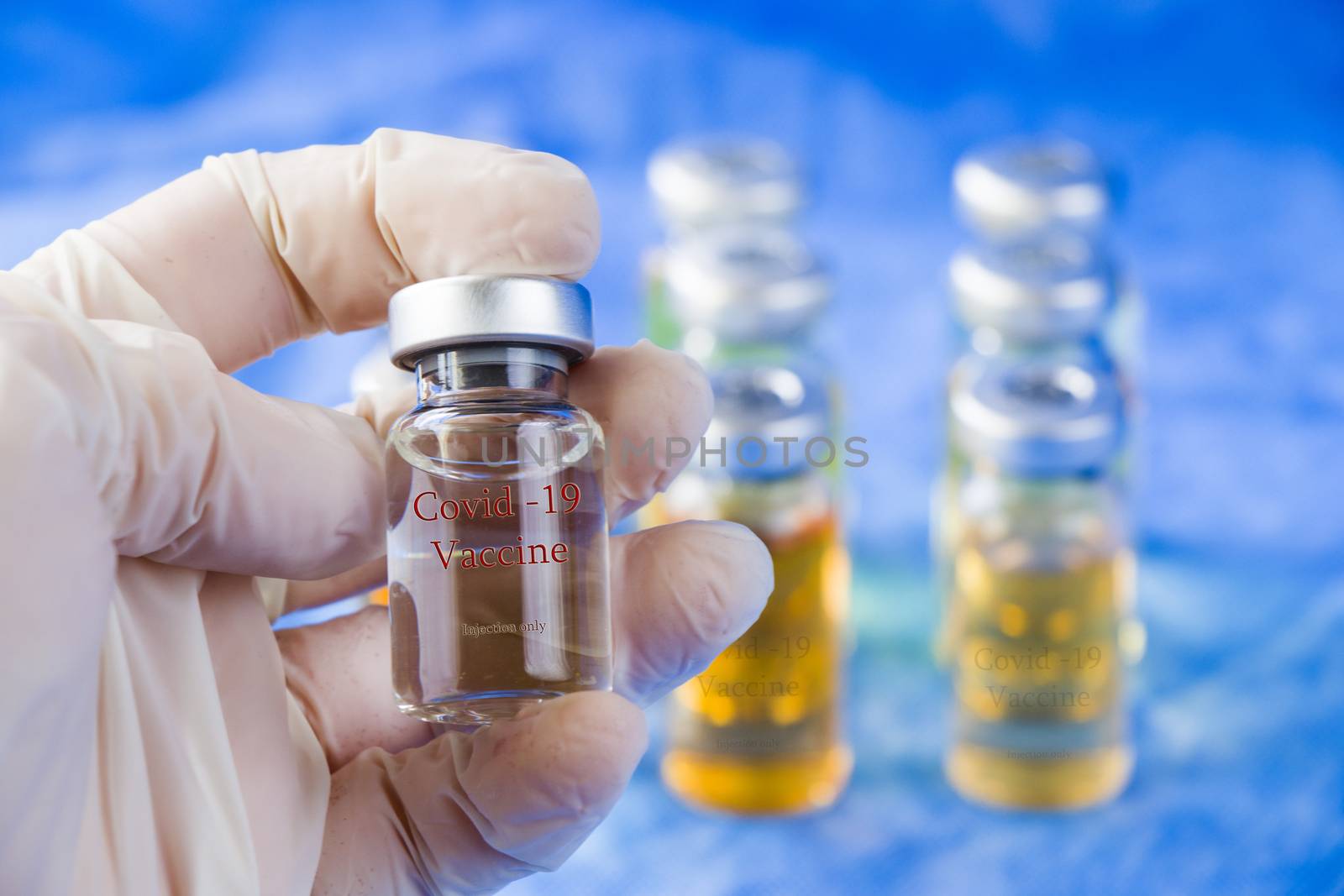 Corona virus and Covid - 19 doctors hand holding a vaccine, new vaccine in bottles, different color variations of vaccine liquid on the blue background