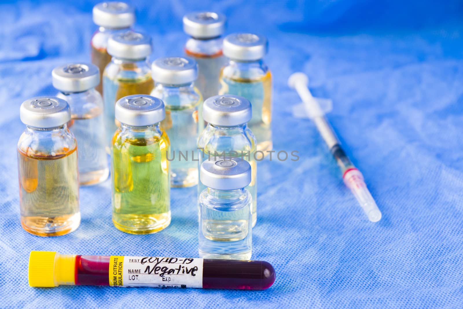 Corona virus and Covid - 19 new vaccine in ampules and blood tube, different color variations of vaccine on the blue background