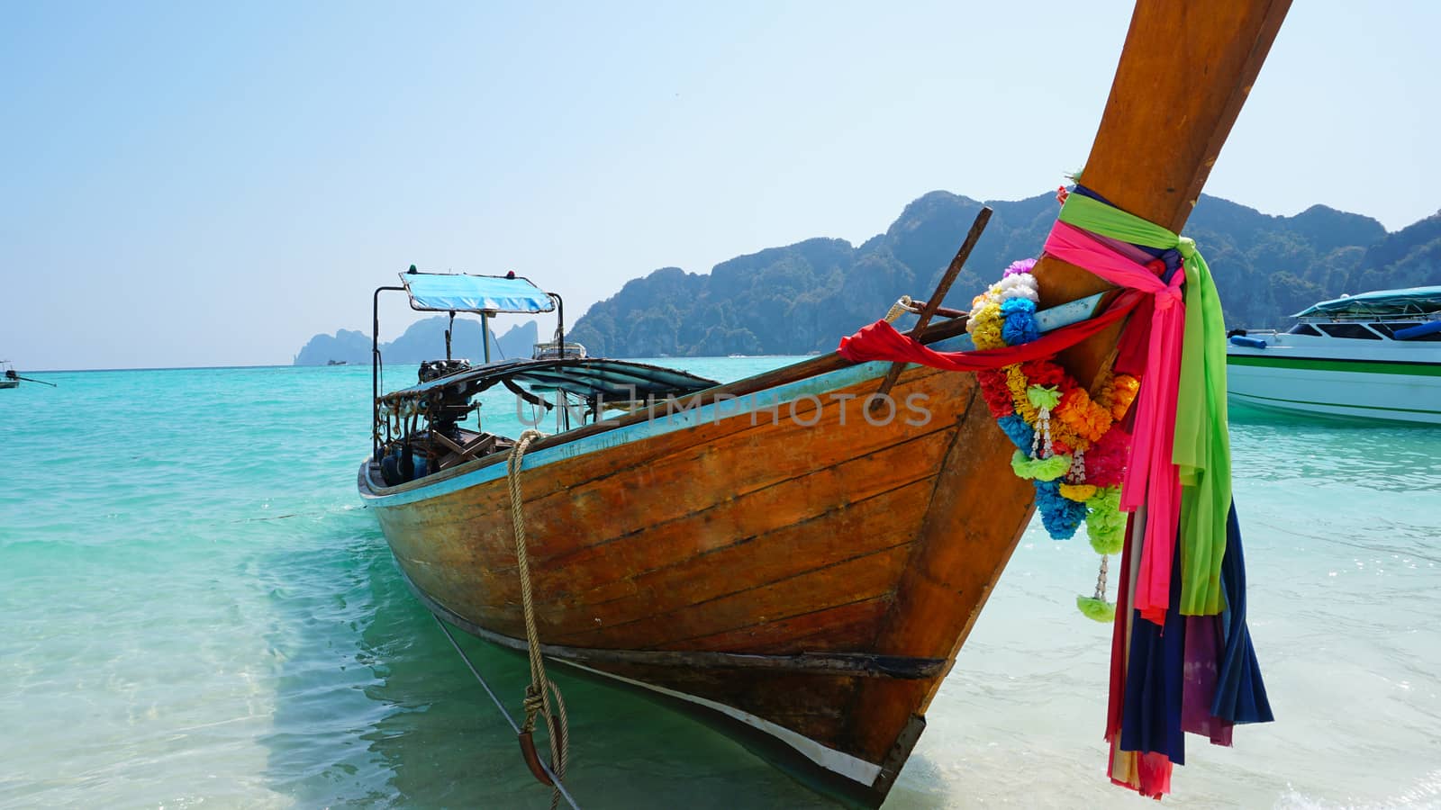 Sea long-tailed boats. Traditional Thai boats. Bright colored ribbons. Turquoise, blue, clear water. White sand on the beach. Holiday boat. A small wave. Travel to Asia. The Island Of Phi Phi Don.