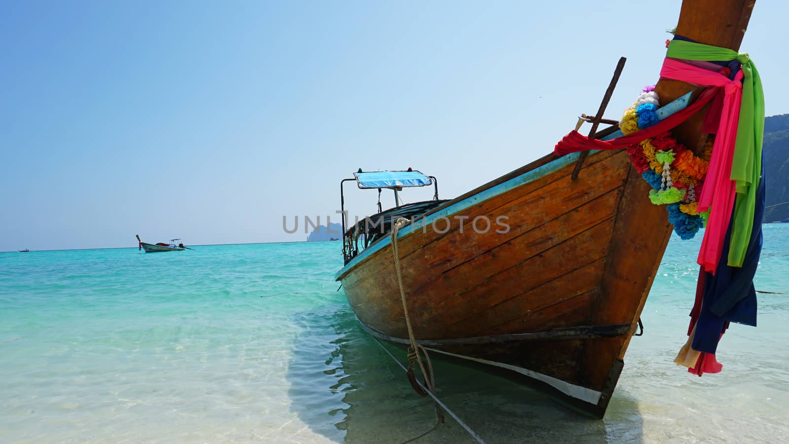 Sea long-tailed boats. Traditional Thai boats. Bright colored ribbons. Turquoise, blue, clear water. White sand on the beach. Holiday boat. A small wave. Travel to Asia. The Island Of Phi Phi Don.