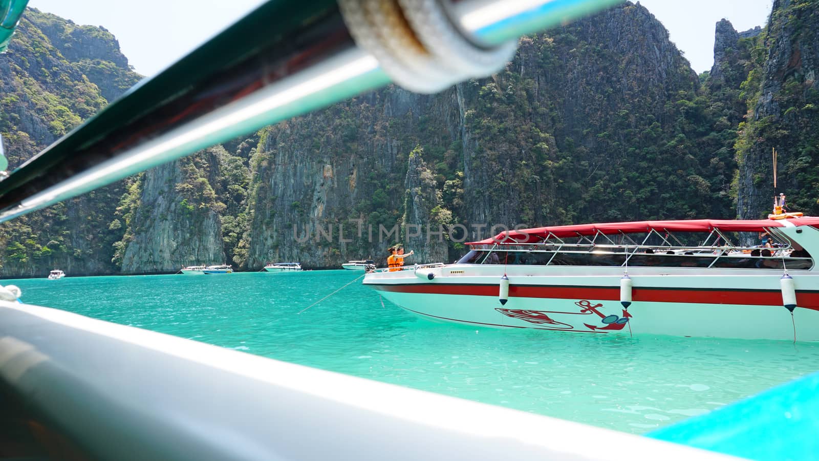 Blue water, green hills and steep rocks. The boat sails near the island. Boat with tourists in the Bay. Steep cliffs and caves. Group of tourists on the boat. Sea excursion. Water gradient.