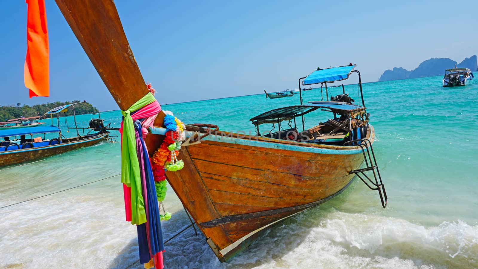 Sea long-tailed boats. Traditional Thai boats. Bright colored ribbons. Turquoise, blue, clear water. White sand on the beach. Holiday boat. A small wave. Travel to Asia. The Island Of Phi Phi Don.