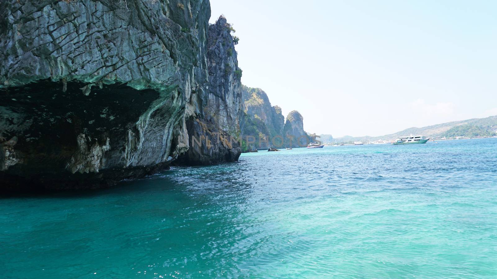 A large cave with hanging stalactites. Viking cave in Thailand. Turquoise clear water. Large blocks of gray stones. A small Bush grows. The entrance from the ocean. Unusual place.