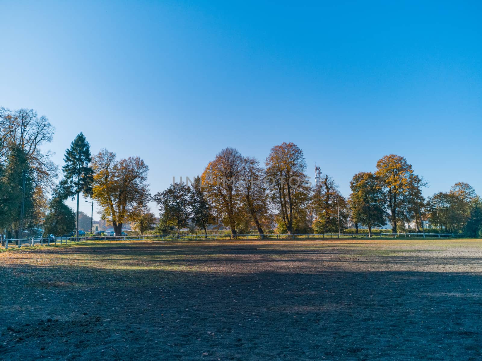 Empty paddock for horses with colorful fall trees around by Wierzchu