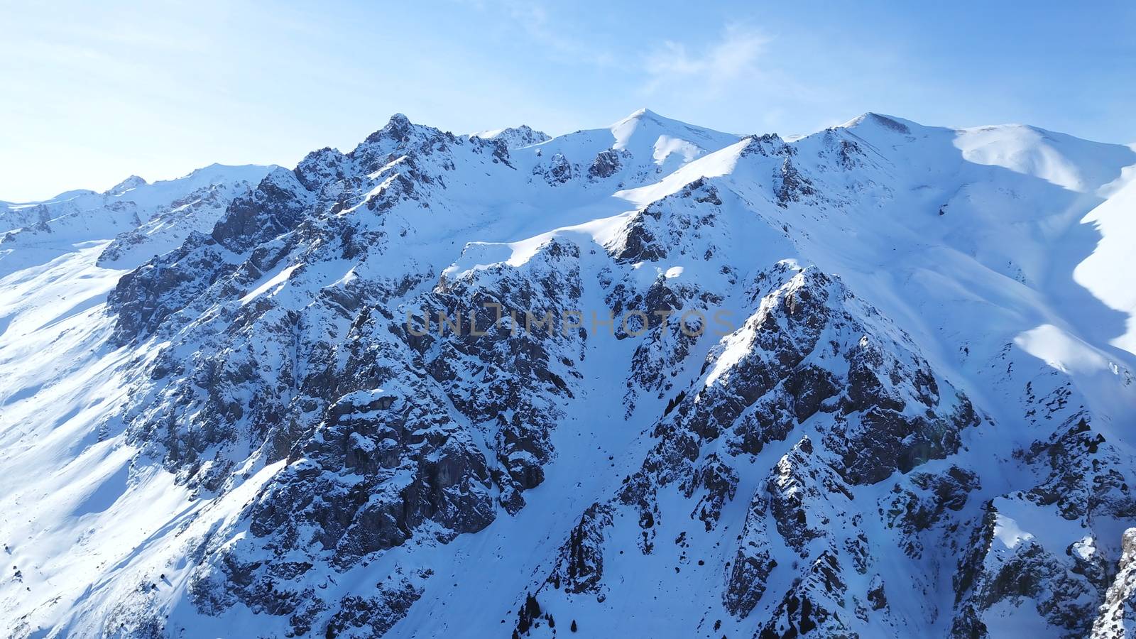 Huge rocks covered with snow. Dangerous terrain. High mountains, cliffs, and large rocks. Shadow from the sun's rays. Top and side view from the drone. An epic place. The Mountains Of Almaty.