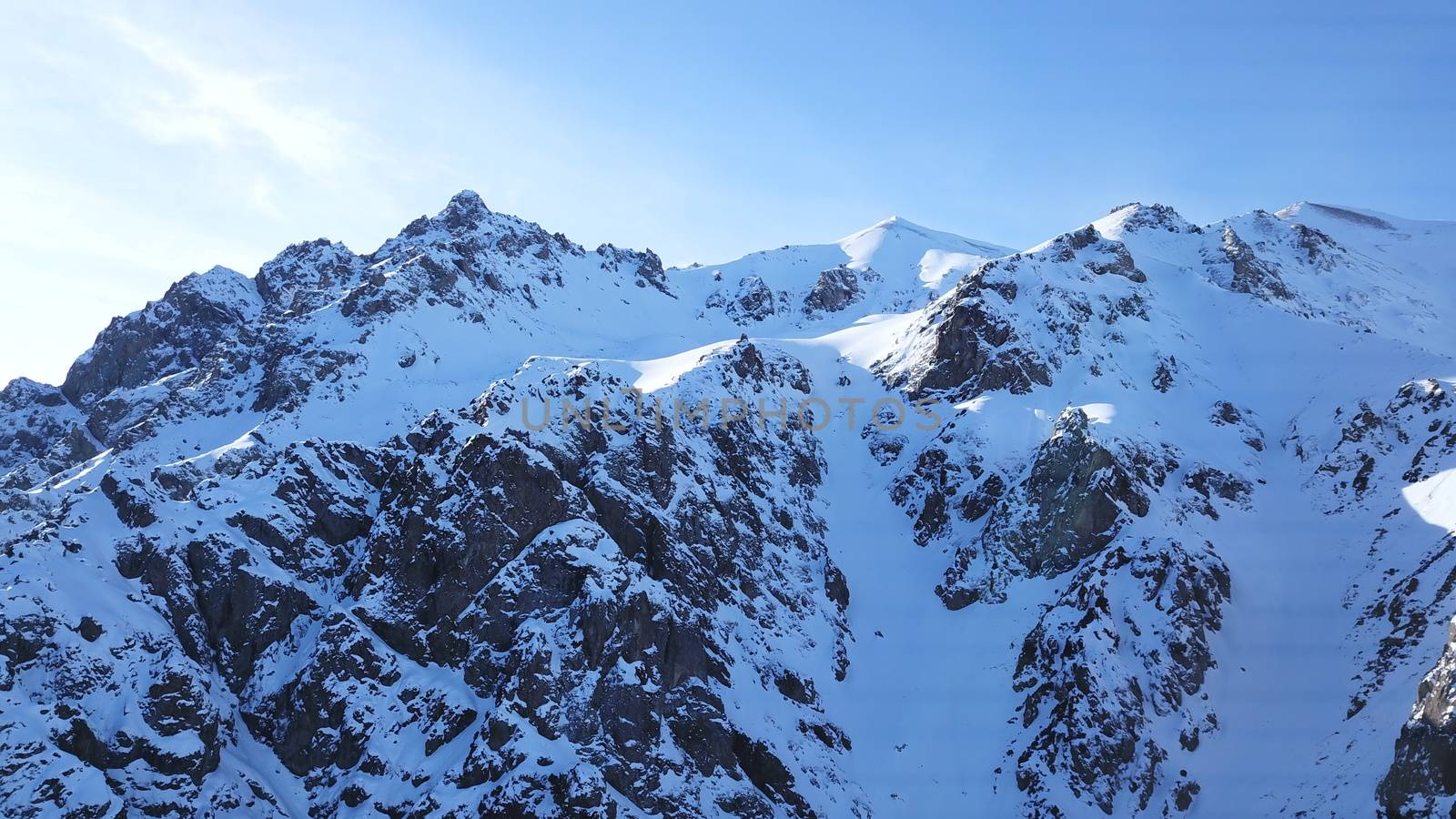Huge rocks covered with snow. Dangerous terrain. High mountains, cliffs, and large rocks. Shadow from the sun's rays. Top and side view from the drone. An epic place. The Mountains Of Almaty.