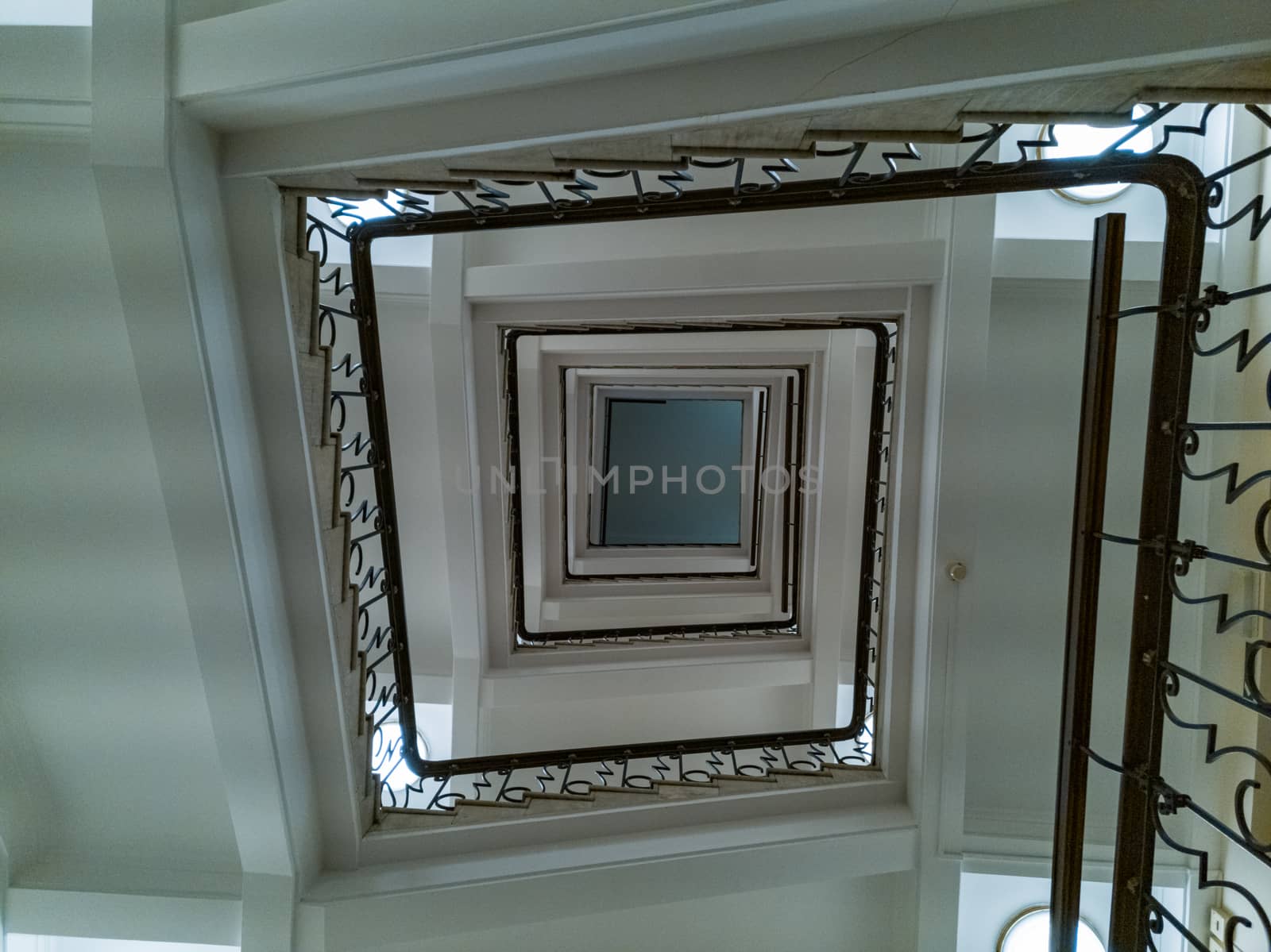 Upward view to old square spiral staircase with metal railings