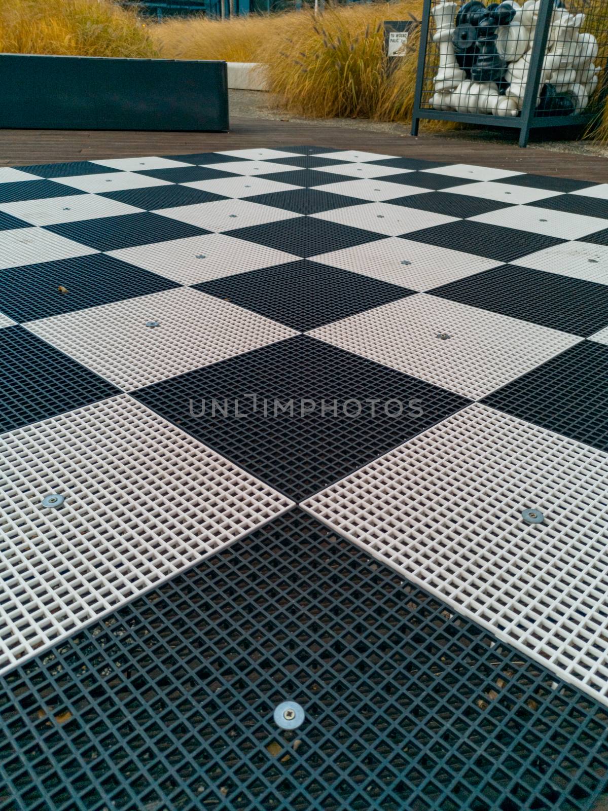 Plastic chessboard with plastic chess pieces at corporate square by Wierzchu