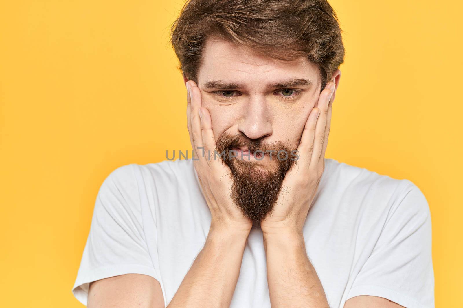 Man in white t-shirt emotions studio gestures with hands displeased facial expression yellow background by SHOTPRIME