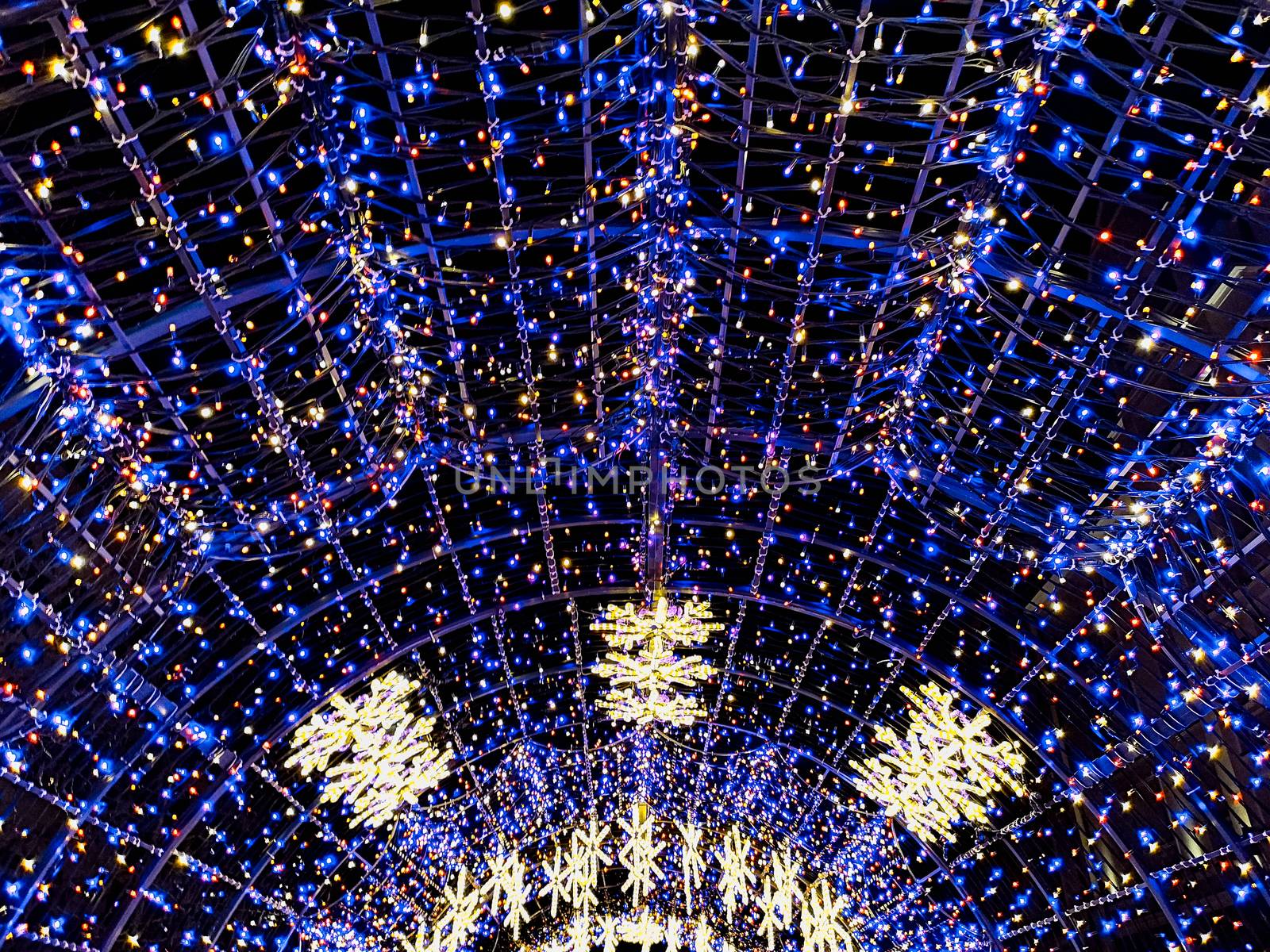 Round colorful christmas tunnel made of christmas lights in city streets by Wierzchu