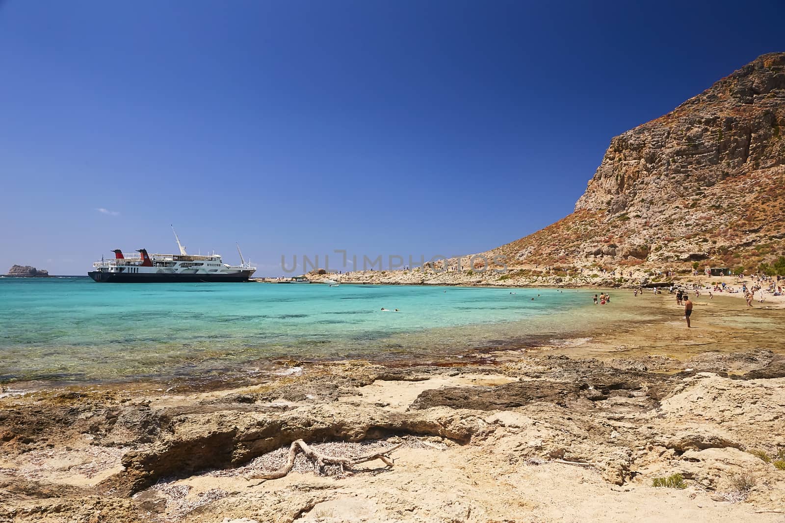 2019, JUNE, THE 4TH: - GREECE, THE CRETE ISLAND, BALOS - The castle on the top of the mountain and the people on the beach below it.