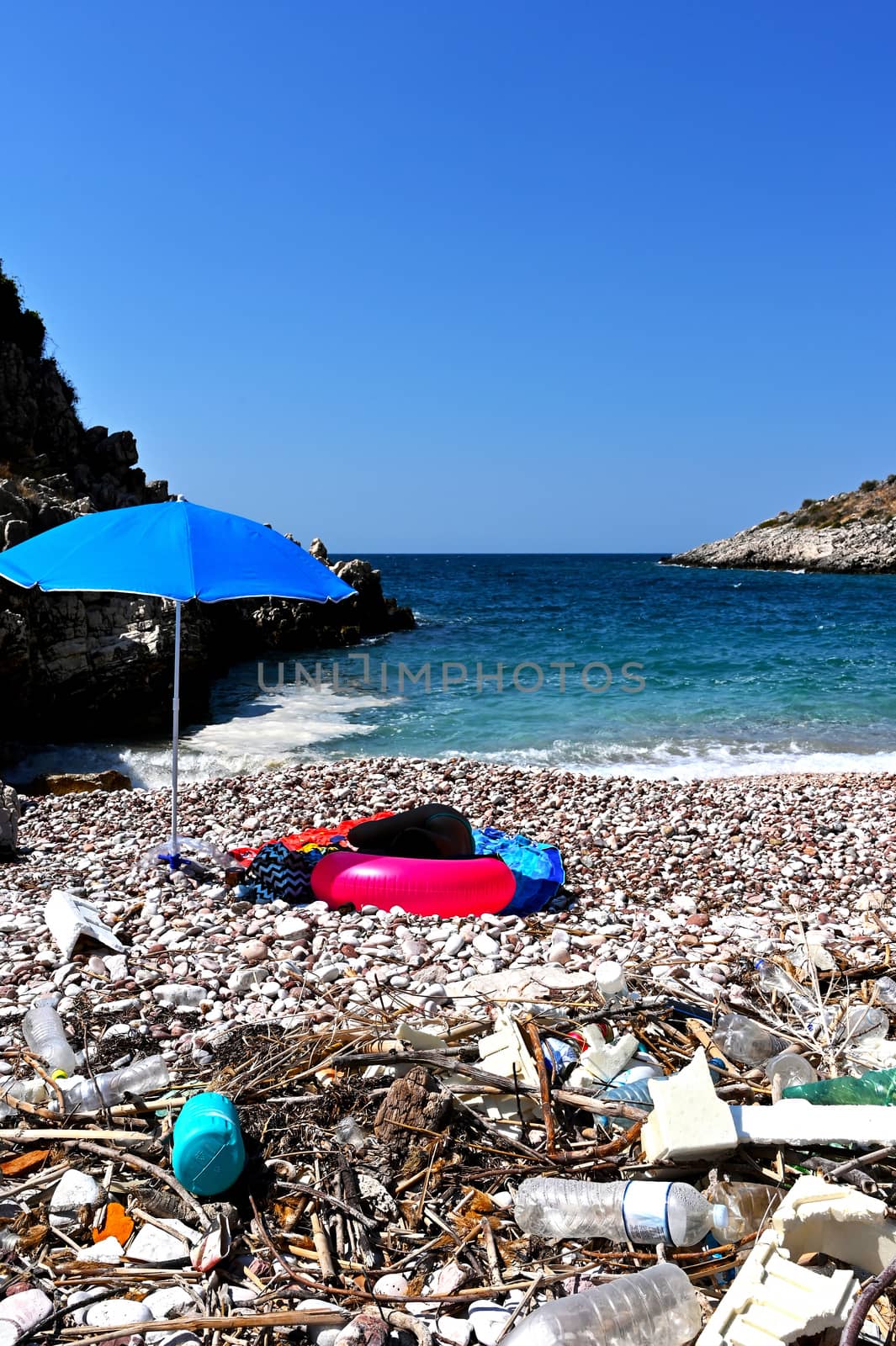 Dirty beach of Albania coast with girl sleeping in background. Empty, used dirty plastic bottles. Environmental pollution. Ecological problem.