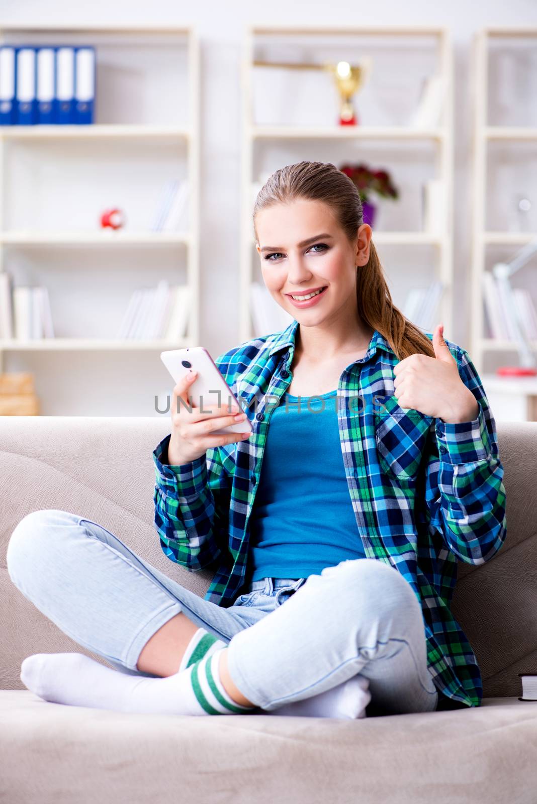 Female student sitting on the sofa with mobile