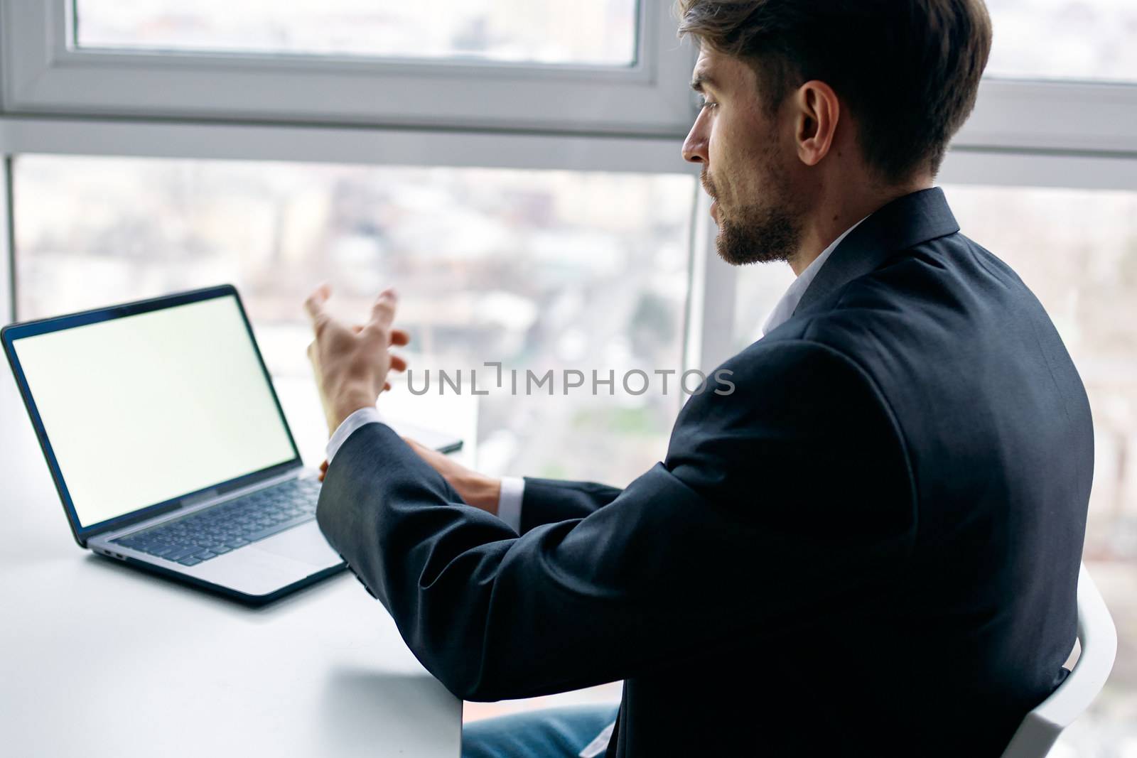 Business man in the office at his desk in front of a laptop communication by SHOTPRIME