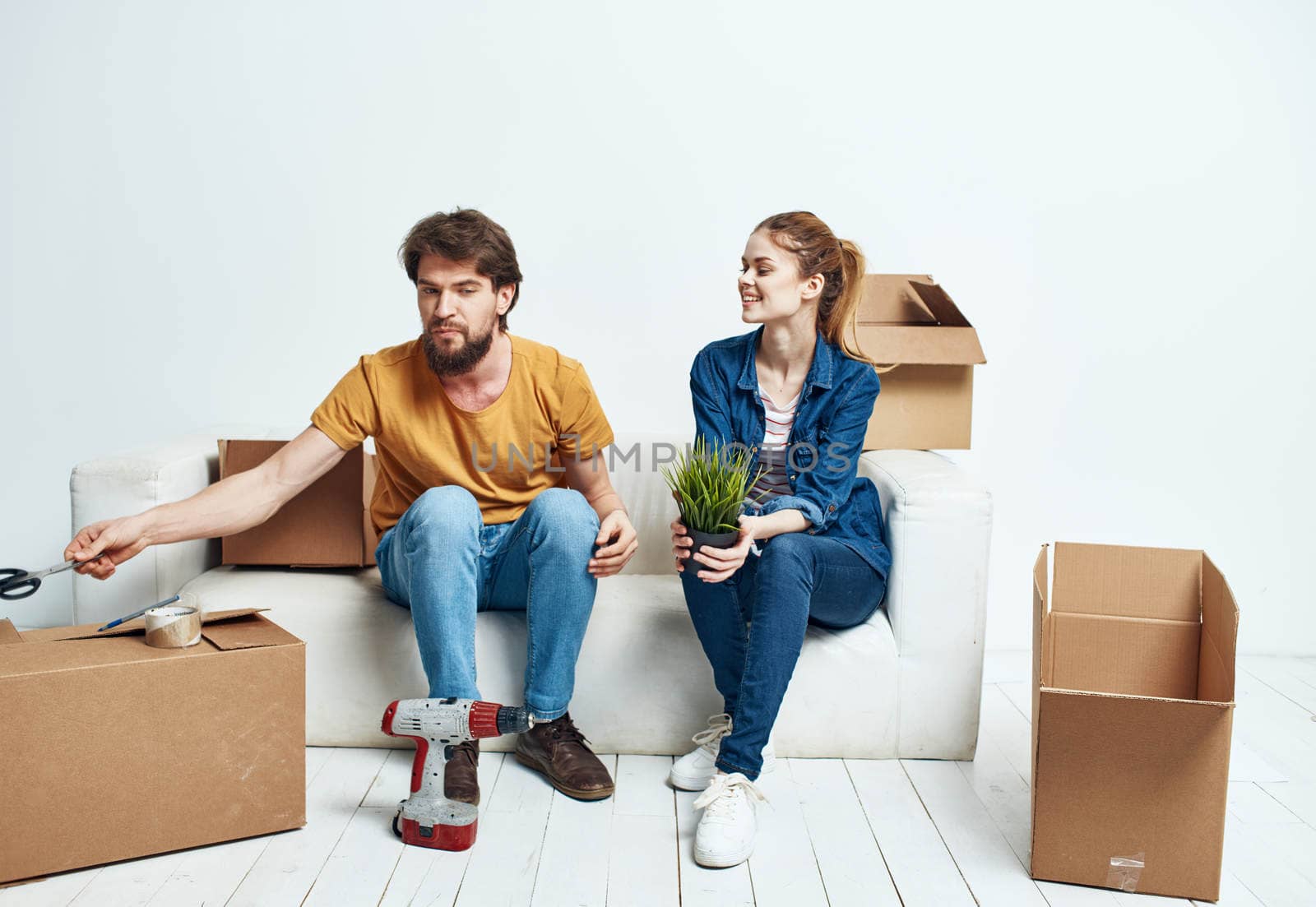 A man and a woman are sitting on the couch near the boxes with things moving the interior of the room. High quality photo