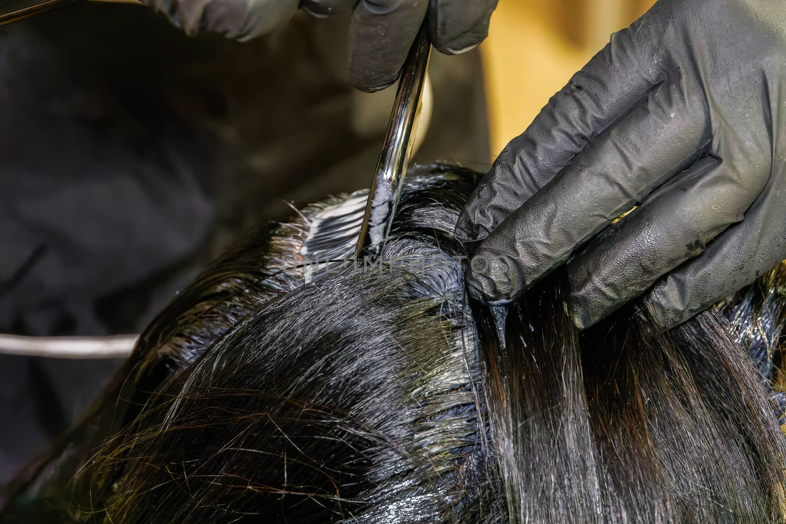 At-home hair coloring styling with a solid level of black paint mix coverage, using a brush on the hair roots.