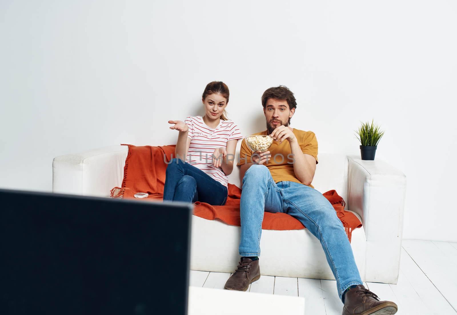 Man and woman on sofa with flower room interior and TV screen. High quality photo