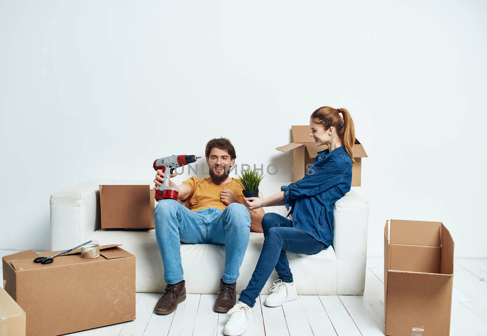 cheerful man and woman on the couch moving interior cardboard boxes. High quality photo