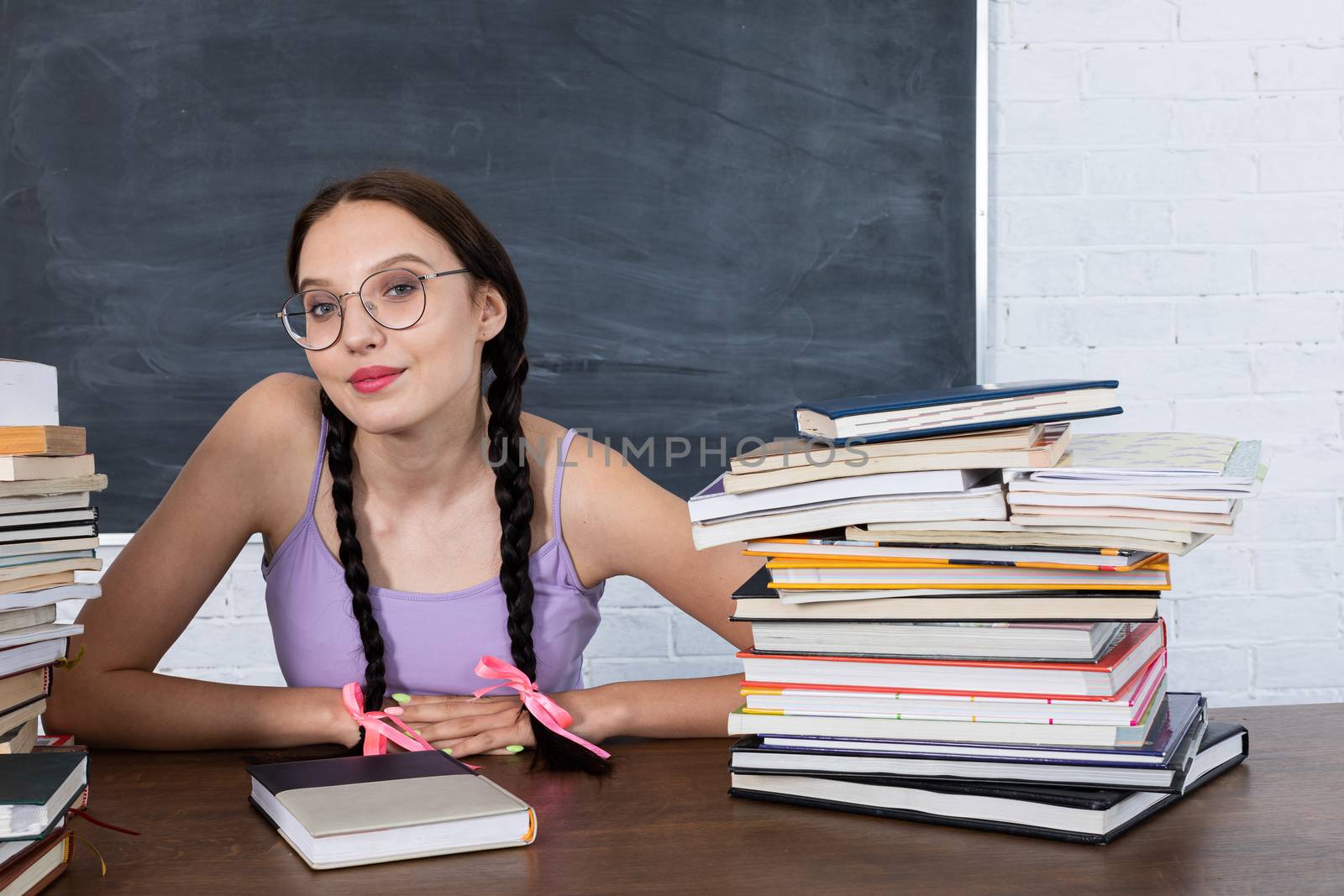 A young student is waiting for the next assignment and reading to be read. After reading all the books lying nearby, the girl is waiting for the exam. by fotodrobik