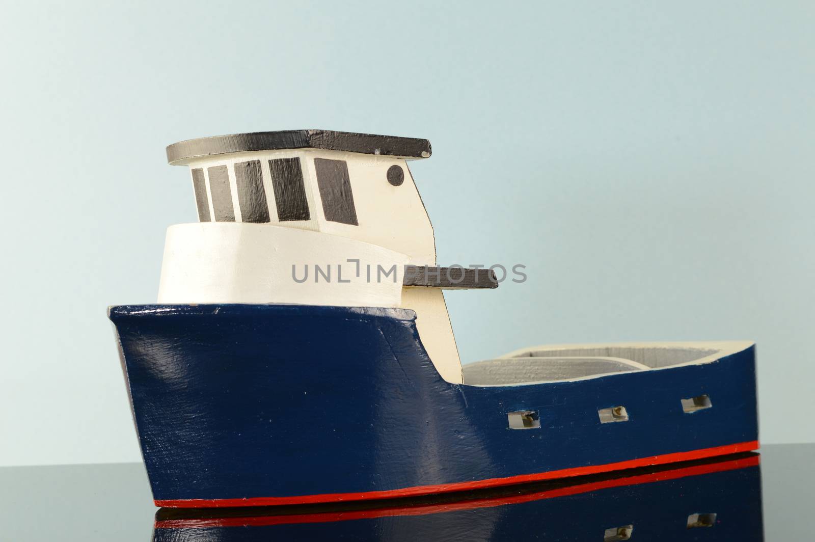 A closeup view of a blue tug boat on the reflected water surface.
