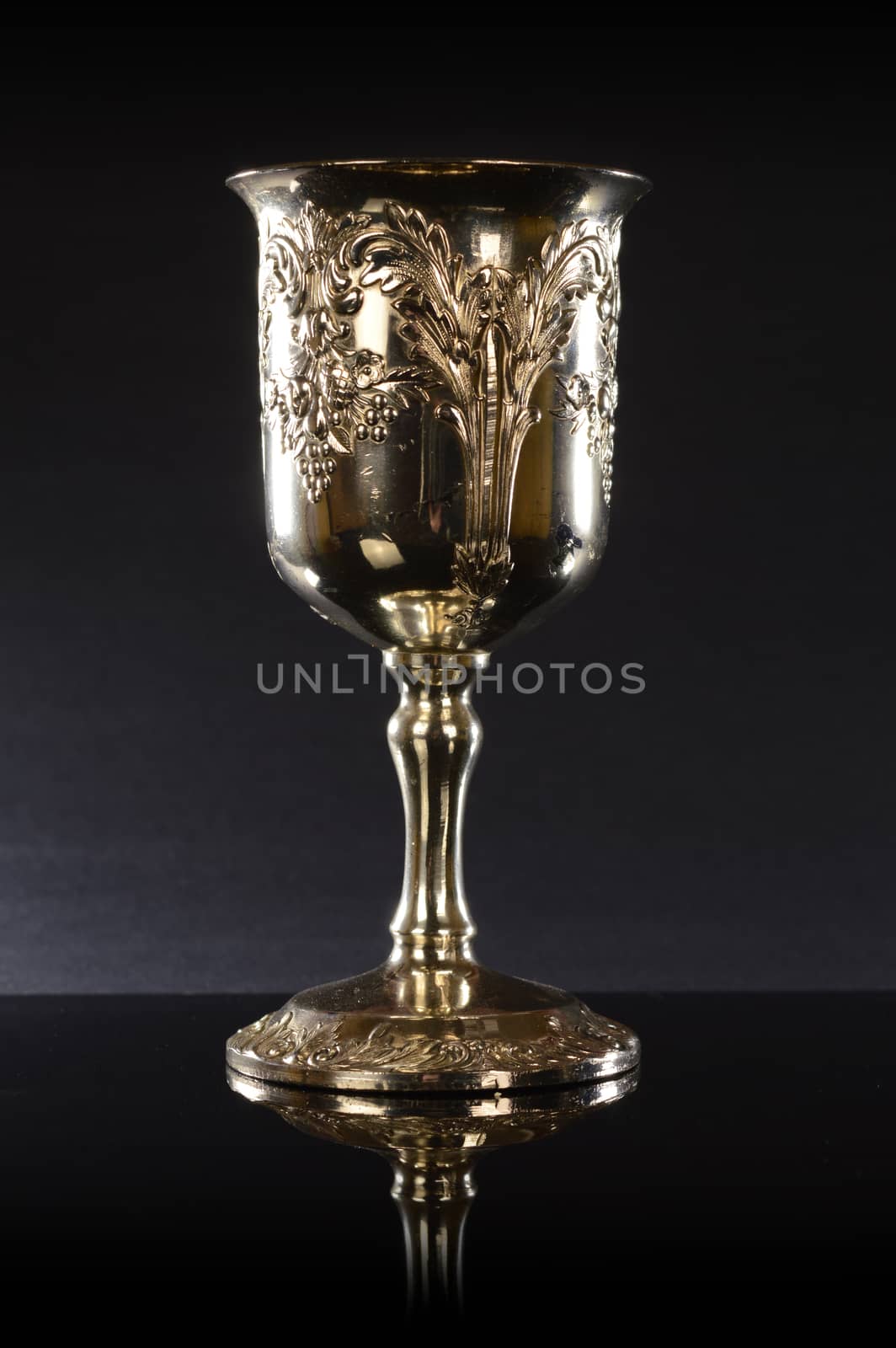 A treasured silver cup over a black reflective background.