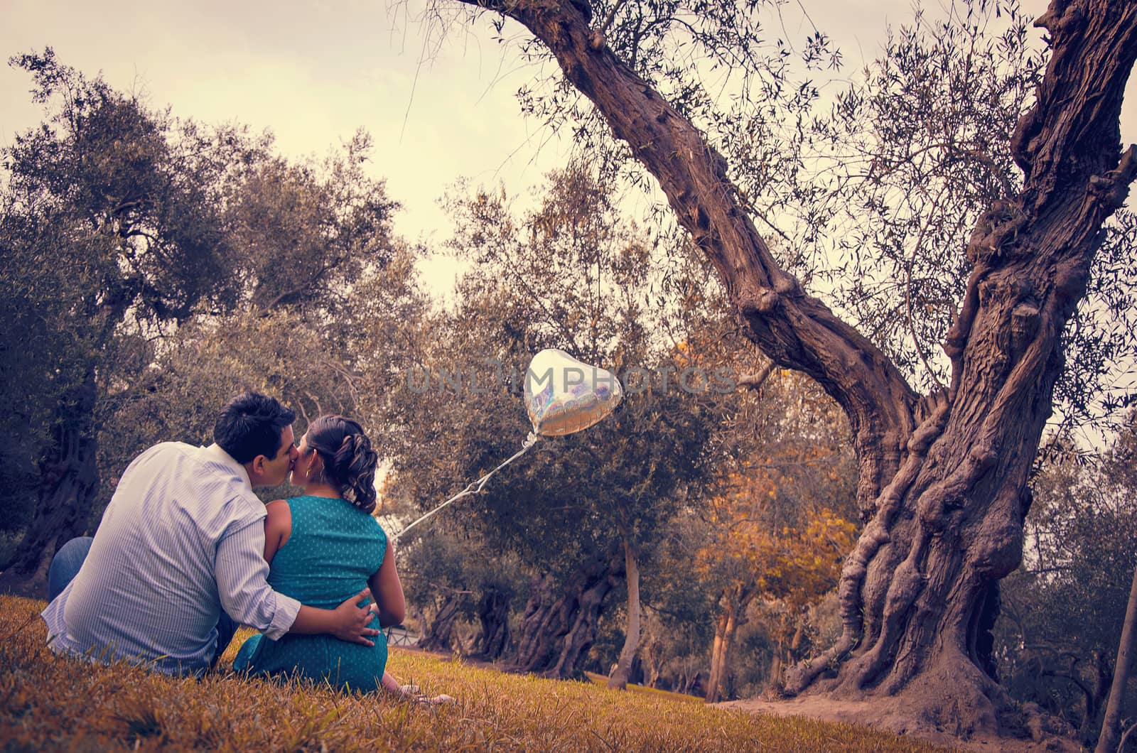 Happy young man piggybacking his girlfriend holding a red heart-shaped balloon