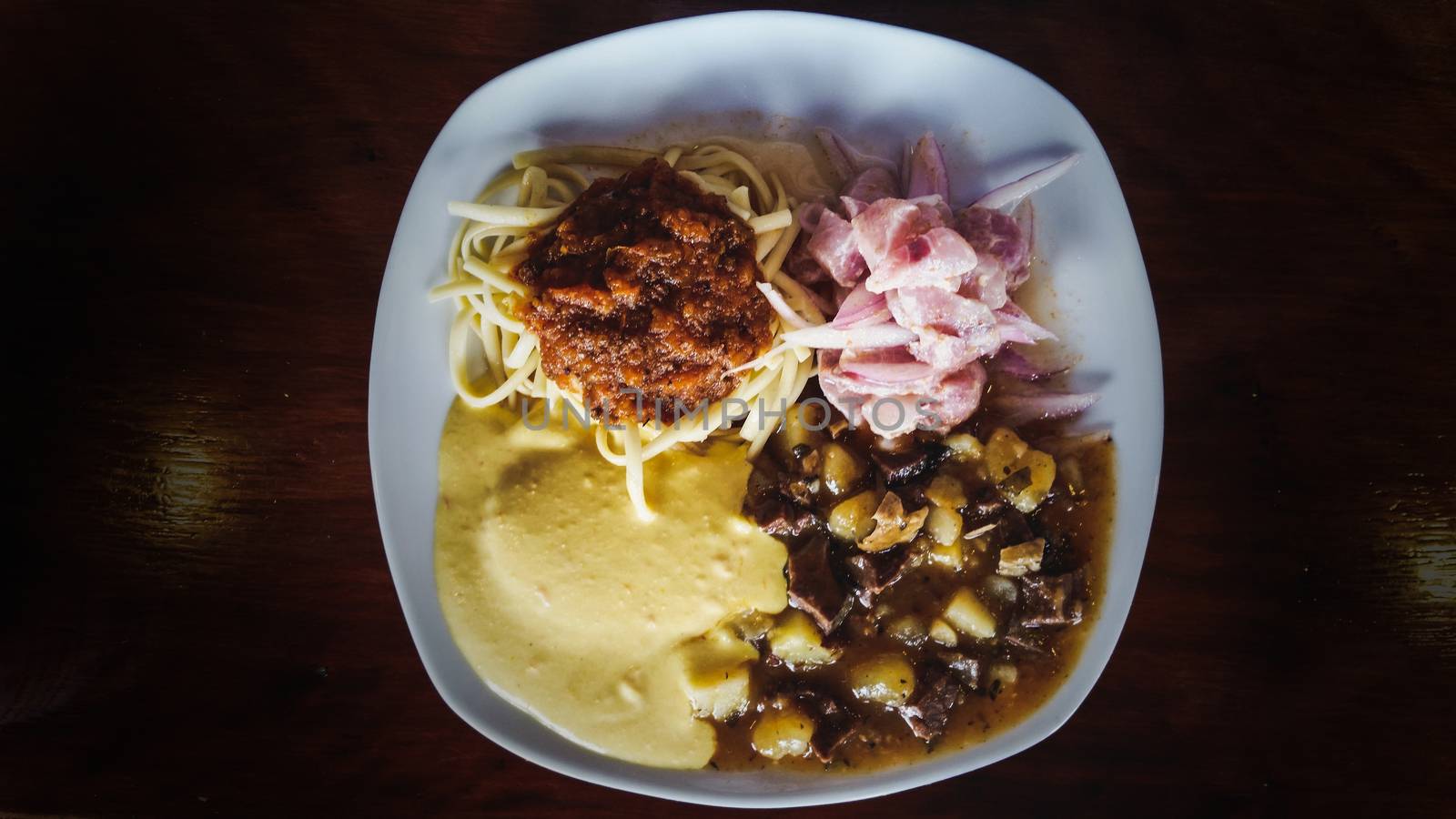 Peruvian cuisine: chanfainita with noodles, ceviche and huancaina sauce served on a flat plate