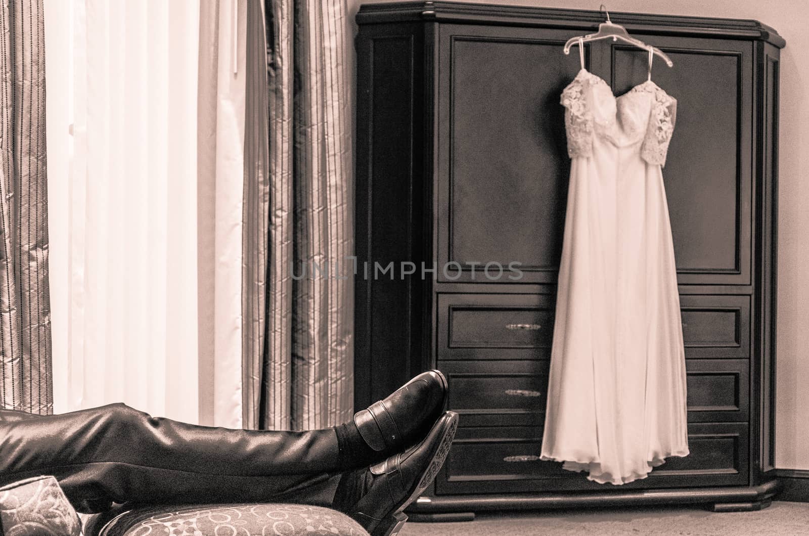 Groom waiting for the bride and the bride's dress hanging